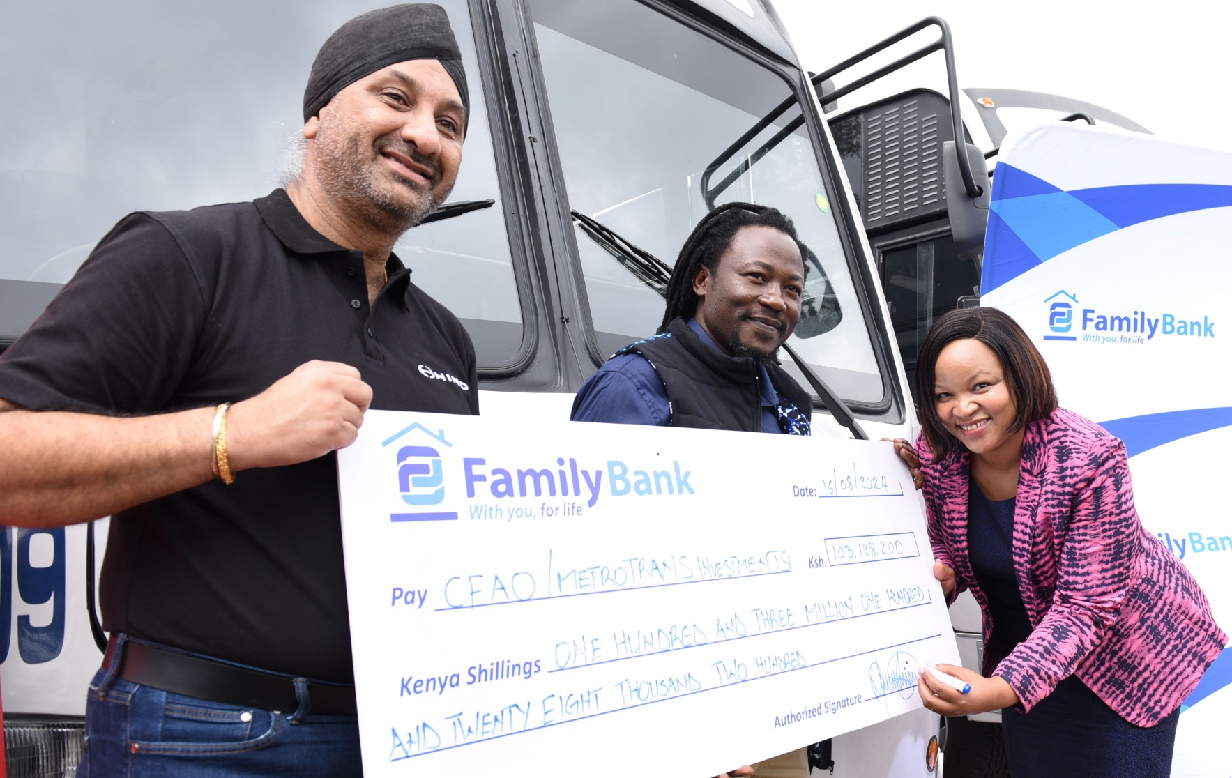 Family Bank CEO Nancy Njau signs a KES. 103 million cheque during the handover of 14 Hino buses financed by the Bank to CFAO Mobility Kenya Group MD Arvinder Reel & Metro Trans Investment Limited Chairman Oscar Omurwa. PHOTO/COURTESY