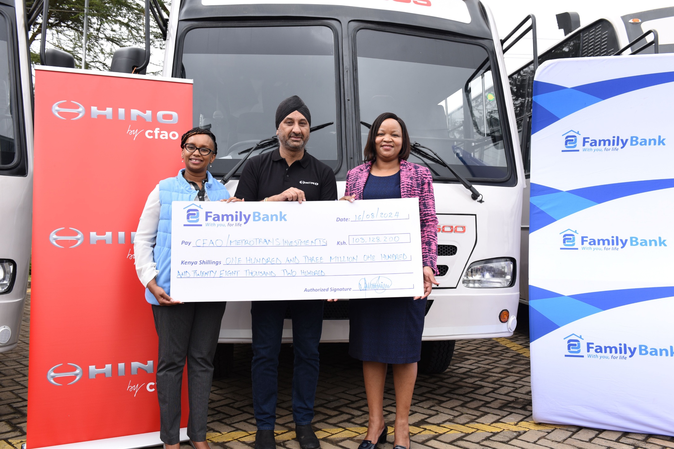 Family Bank CEO Nancy Njau signs a KES. 103 million cheque during the handover of 14 Hino buses financed by the Bank to CFAO Mobility Kenya Group MD Arvinder Reel & Metro Trans Investment Limited Chairman Oscar Omurwa. PHOTO/COURTESY