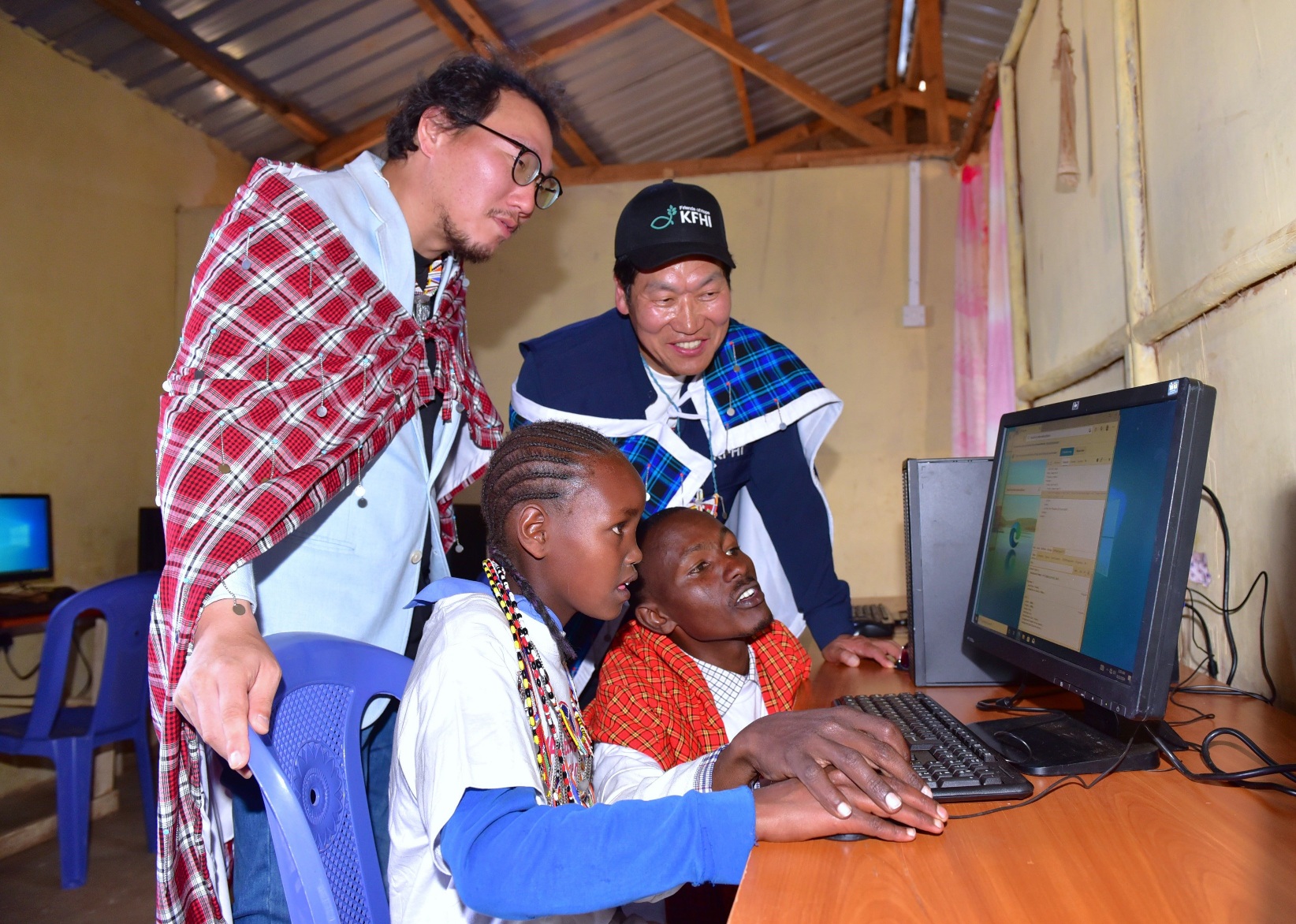 Intinyika Primary School Acting Headteacher James Keshoe Letayian shows Grade 5 pupil Stella Sumpati how to operate a computer, with LG Electronics EA Marketing Manager Changhyun Kim (L) and KFHI Director Chun Jong Hu (R) looking on. The event marked the official handover of various equipment, including solar systems, water tanks, and computers, to address the school's critical infrastructure needs. PHOTO/COURTESY