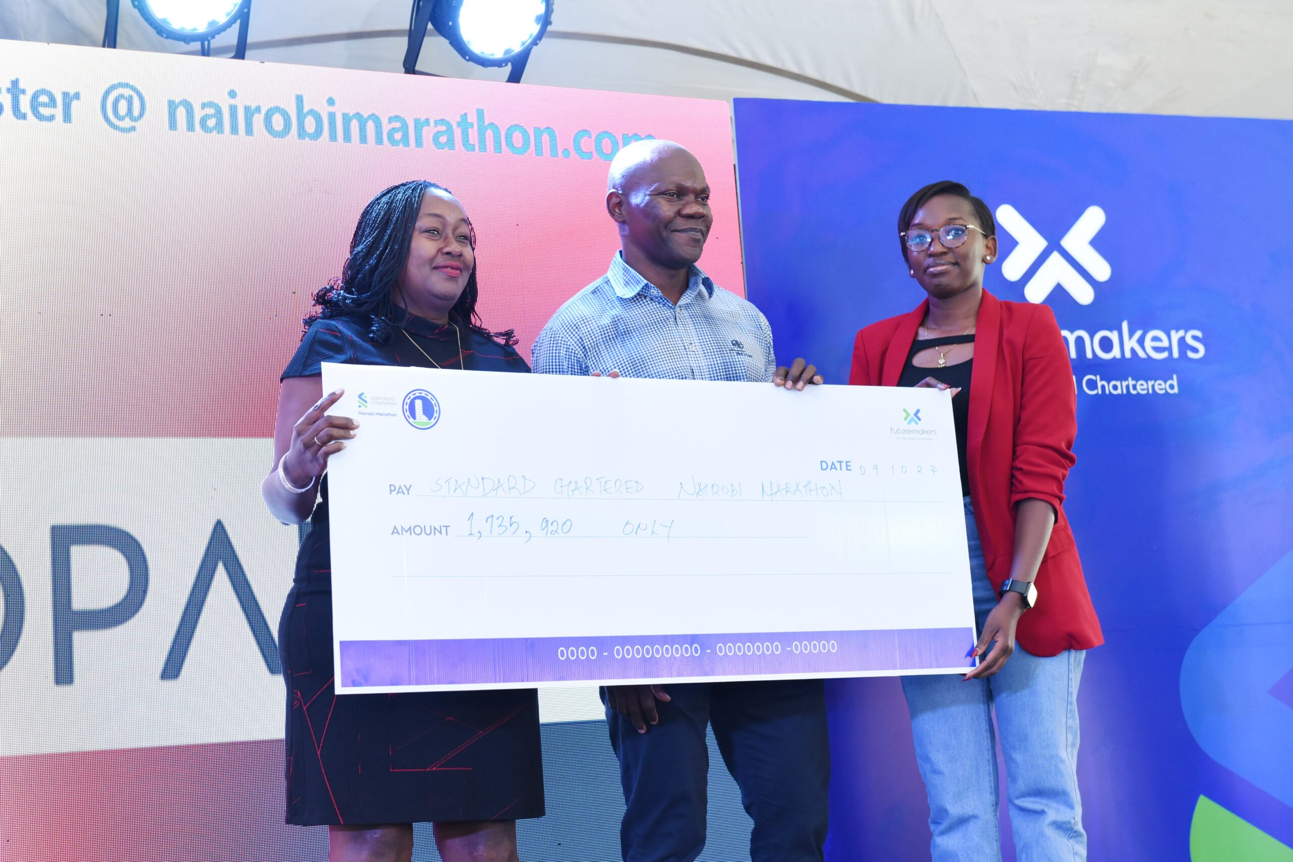 LG Electronics East Africa Head of Corporate Marketing, Jane Kariuki (left) and LG's East Africa Assistant Corporate Marketing Manager (right), Glenda Achieng, present a cheque to Standard Chartered Bank's Head of Compliance, David Mwindi, during a sponsors' breakfast for the 2024 Nairobi Marathon at a Nairobi hotel. In partnership with Opalnet, LG is sponsoring the 2024 Marathon with an in-kind donation worth KES 1.7 million, including five 65-inch TVs and eight XBoom speakers, which will be gifted to winning competitors.